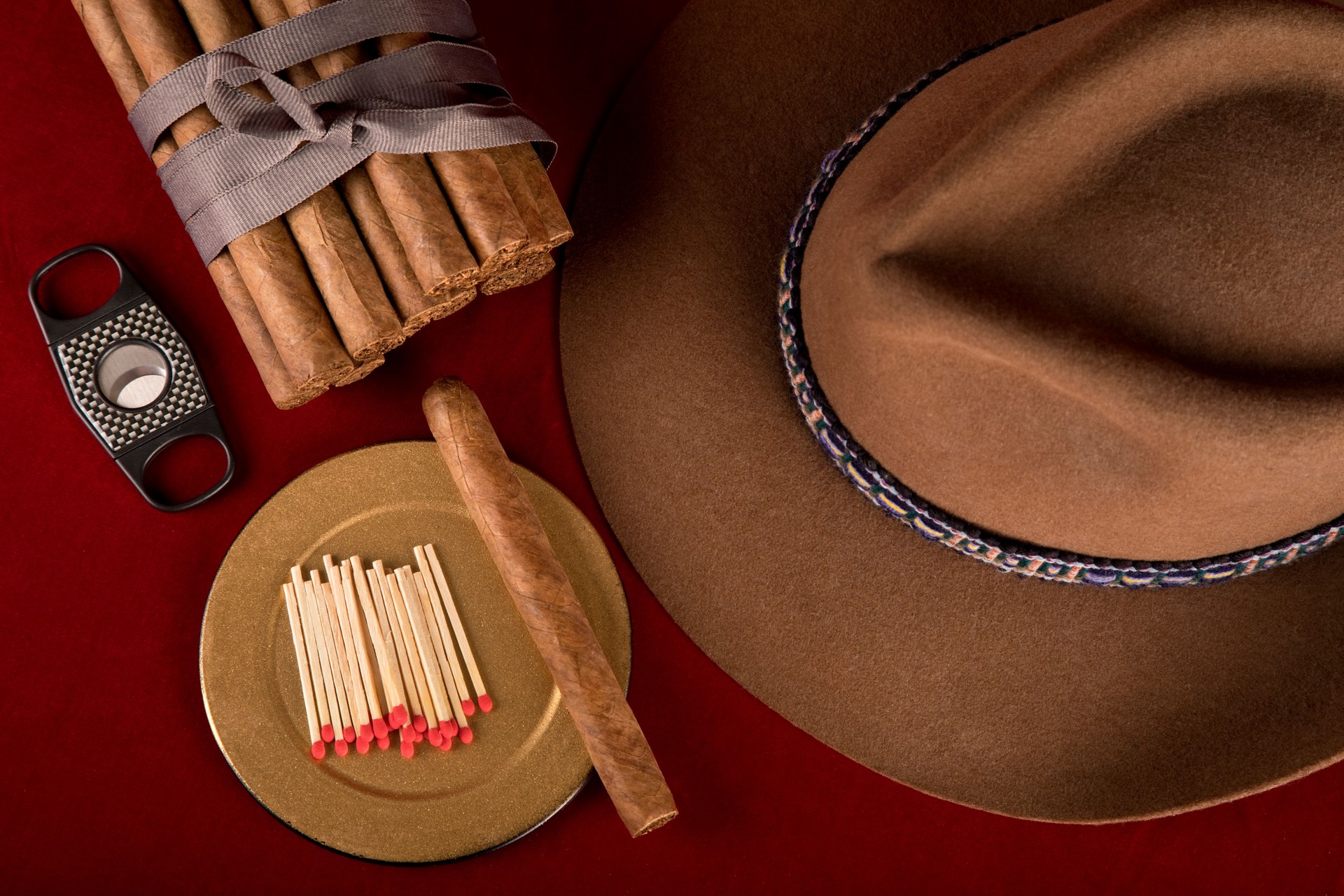 Handmade cigars with cutter, matches, and brown fedora