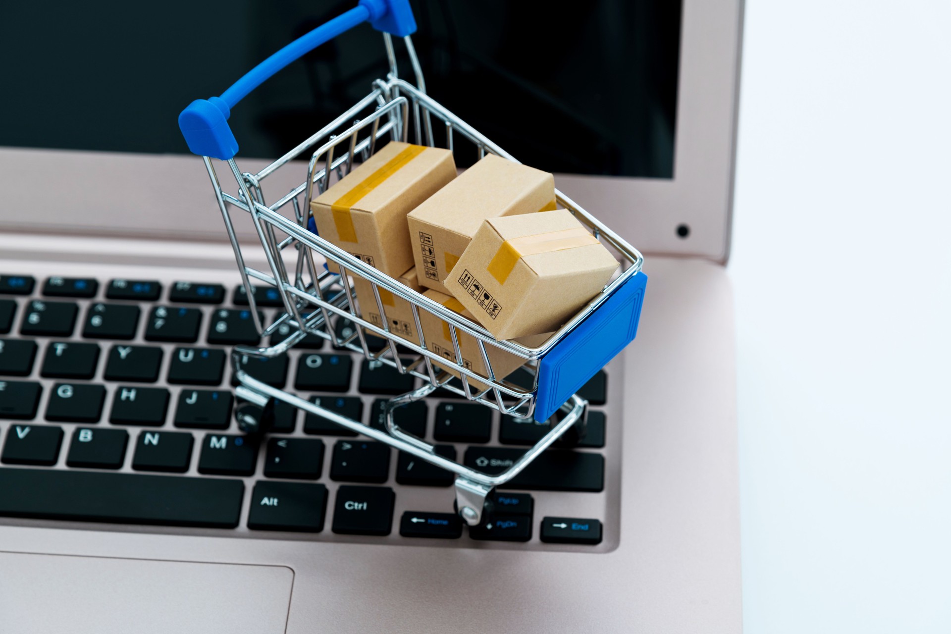 Shopping cart with small boxes on laptop keyboard